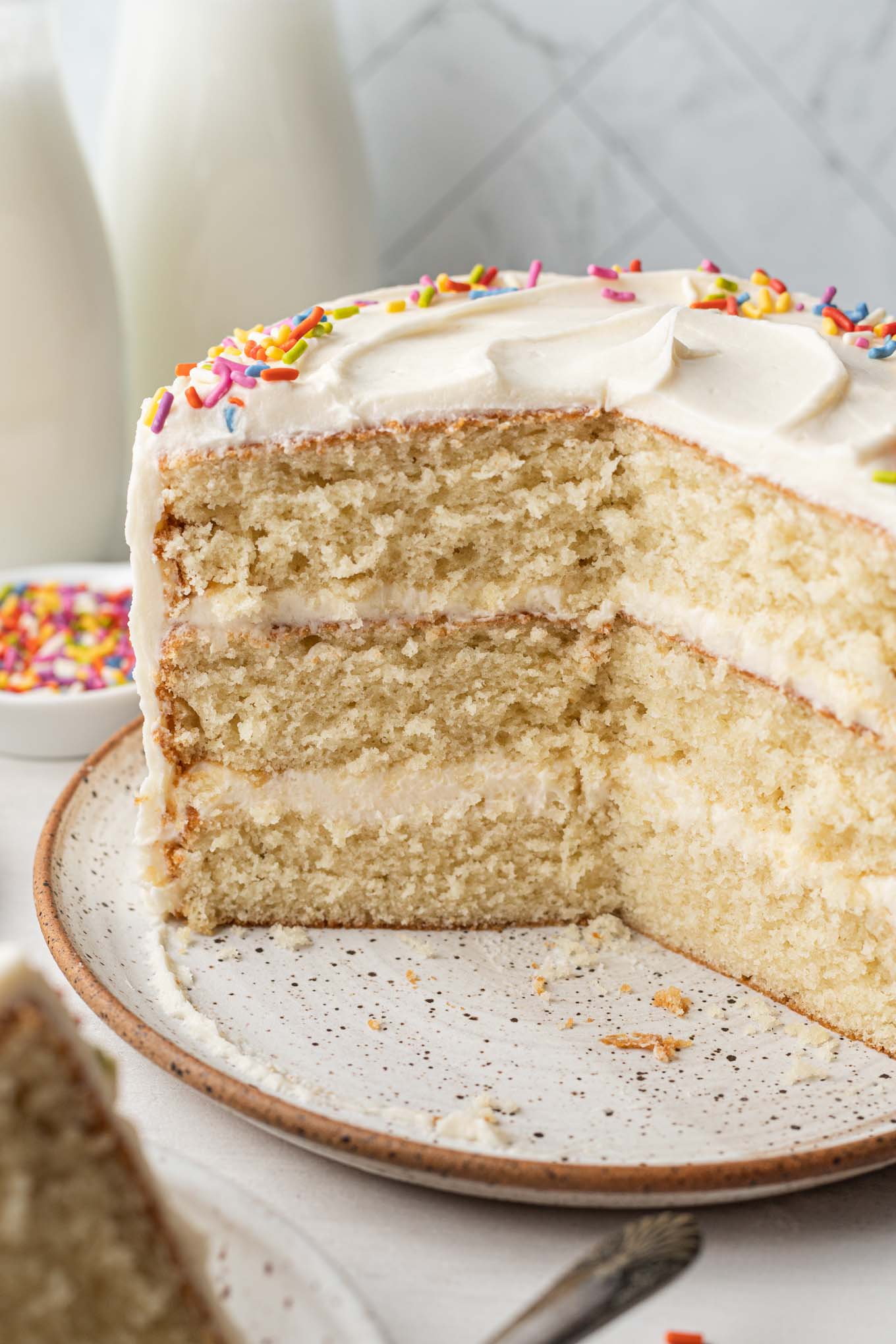 A side view of a small vanilla cake, with slices missing to show the layers inside. 