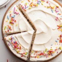 An overhead view of a 6 inch vanilla cake topped with sprinkles.