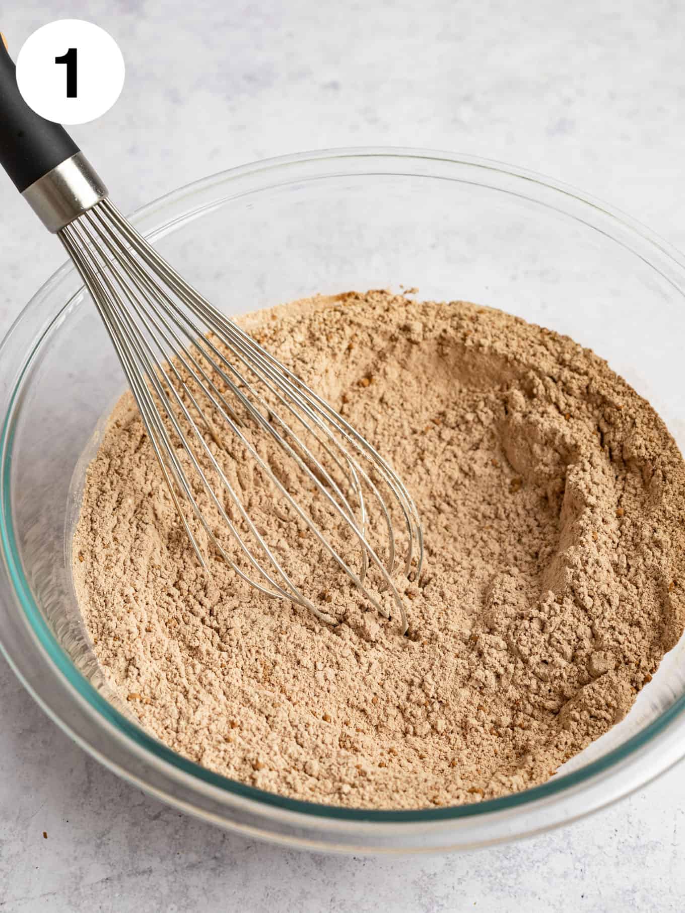 A glass mixing bowl with the dry ingredients mixed together.