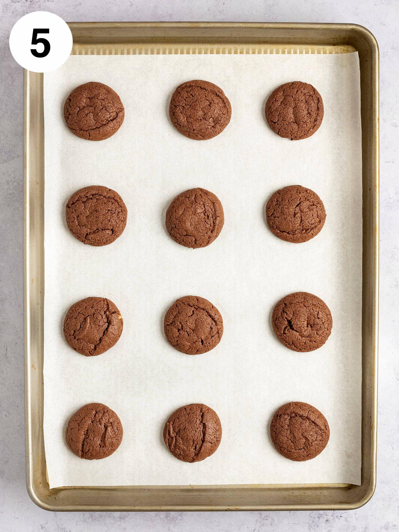 An overhead view of baked chocolate cookies on a baking sheet lined with parchment paper.