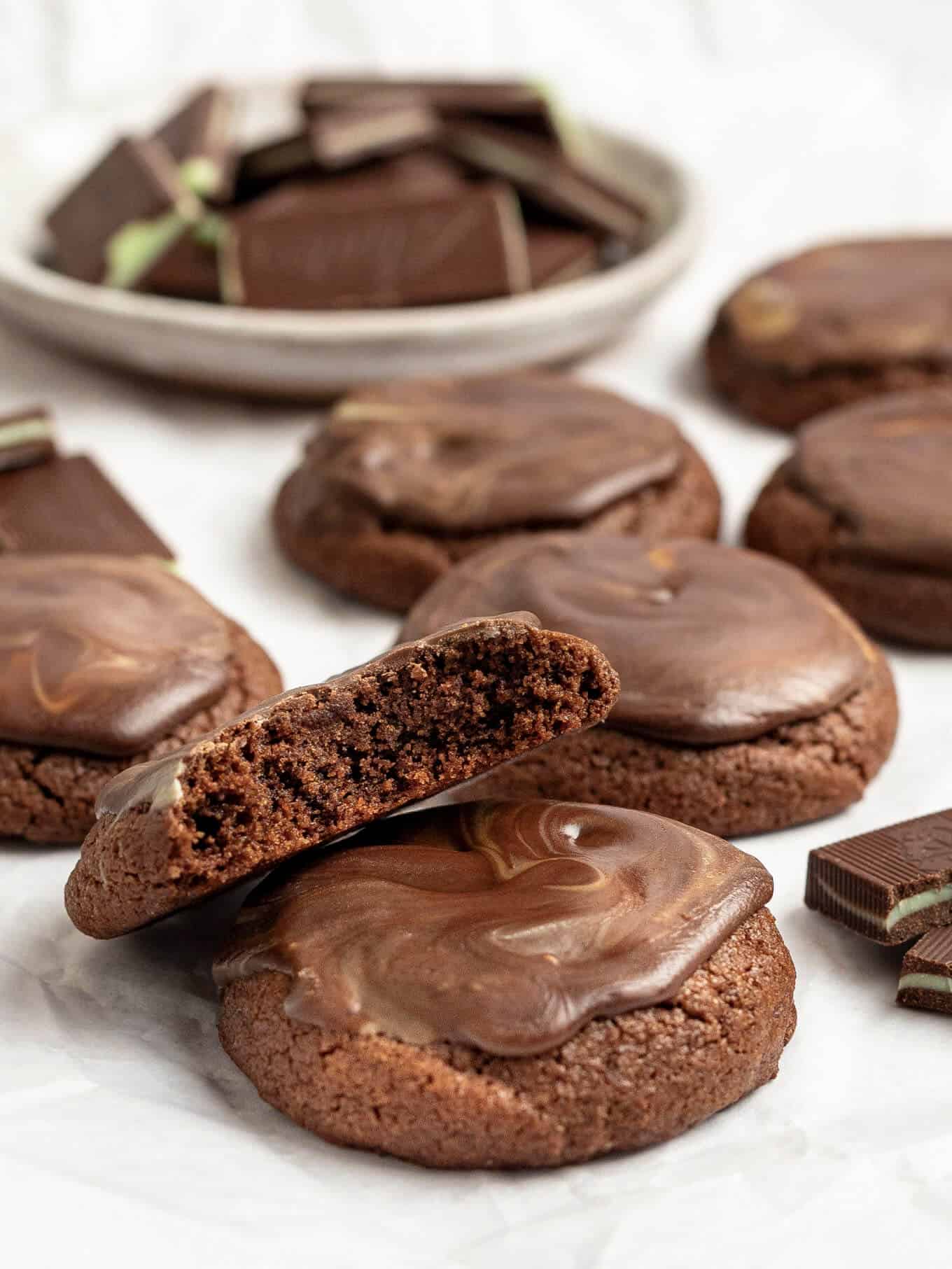 Several andes mint cookies on a piece of white parchment paper. A bowl of Andes mints is sitting in the background.