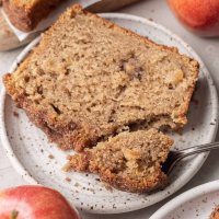 A slice of apple bread on a white speckled plate.