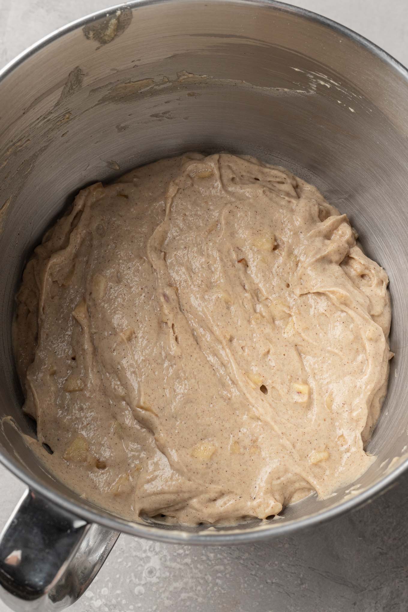 An overhead view of apple quick bread batter in the bowl of a stand mixer. 