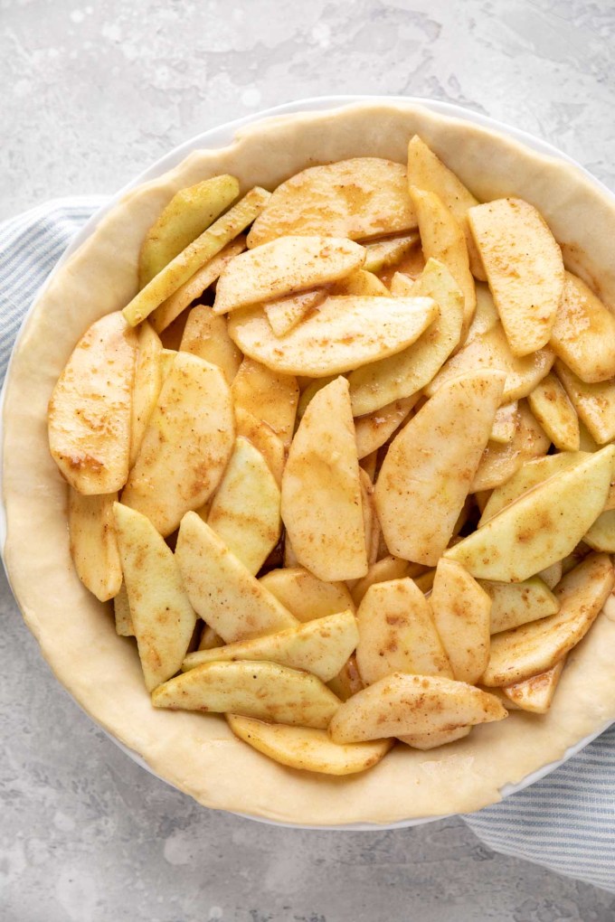 An unbaked pie crust filled with apple pie filling.