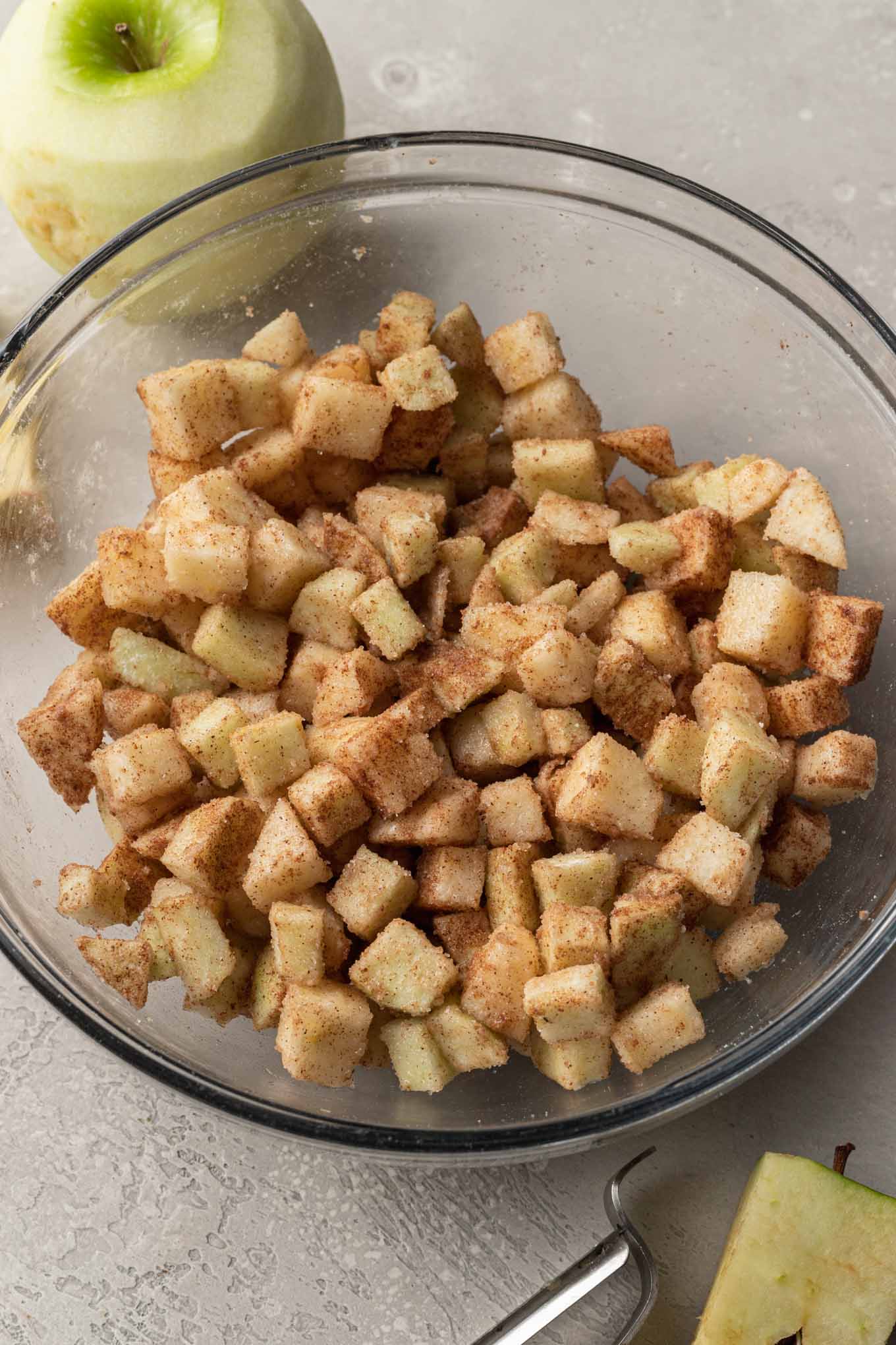 A glass mixing bowl containing apple pie filling. 