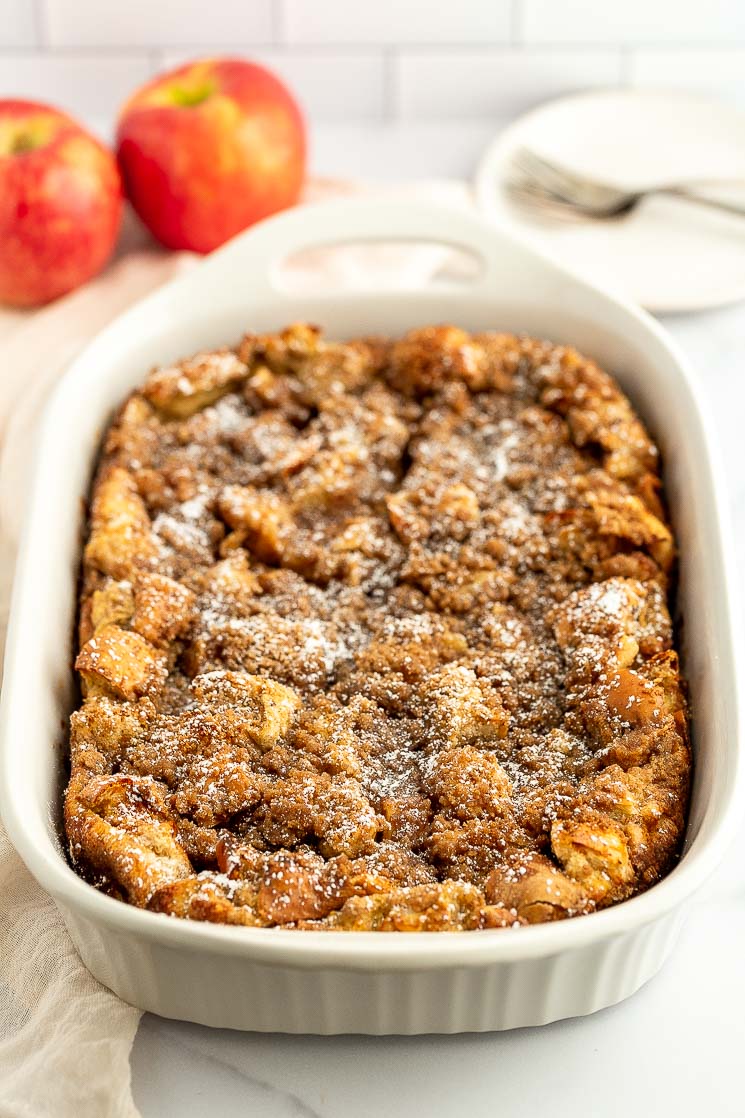 Baked apple french toast casserole in a white baking dish.