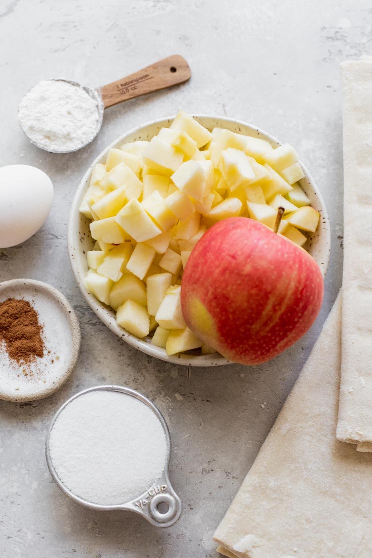 The ingredients for apple turnovers sitting on top of a rustic gray surface.