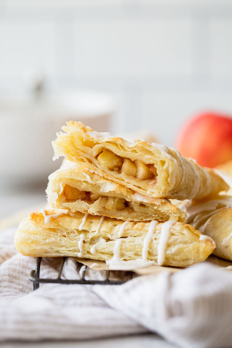 A stack of apple turnovers with one cut in half showing the apple filling.