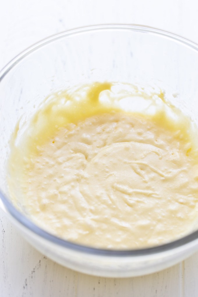 A glass mixing bowl holding the wet ingredients for the cake.