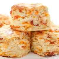 A stack of bacon cheddar biscuits on a white plate.