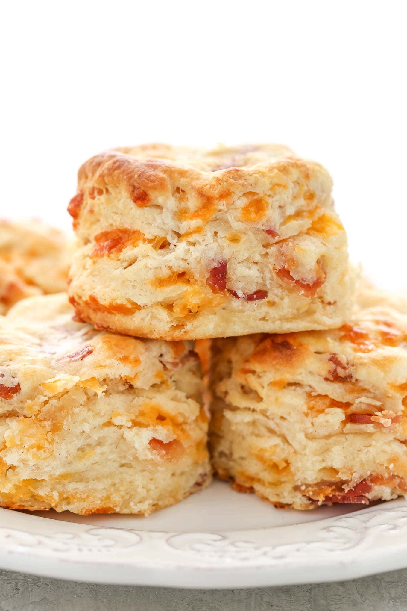 A stack of three bacon cheese biscuits on a white plate. 