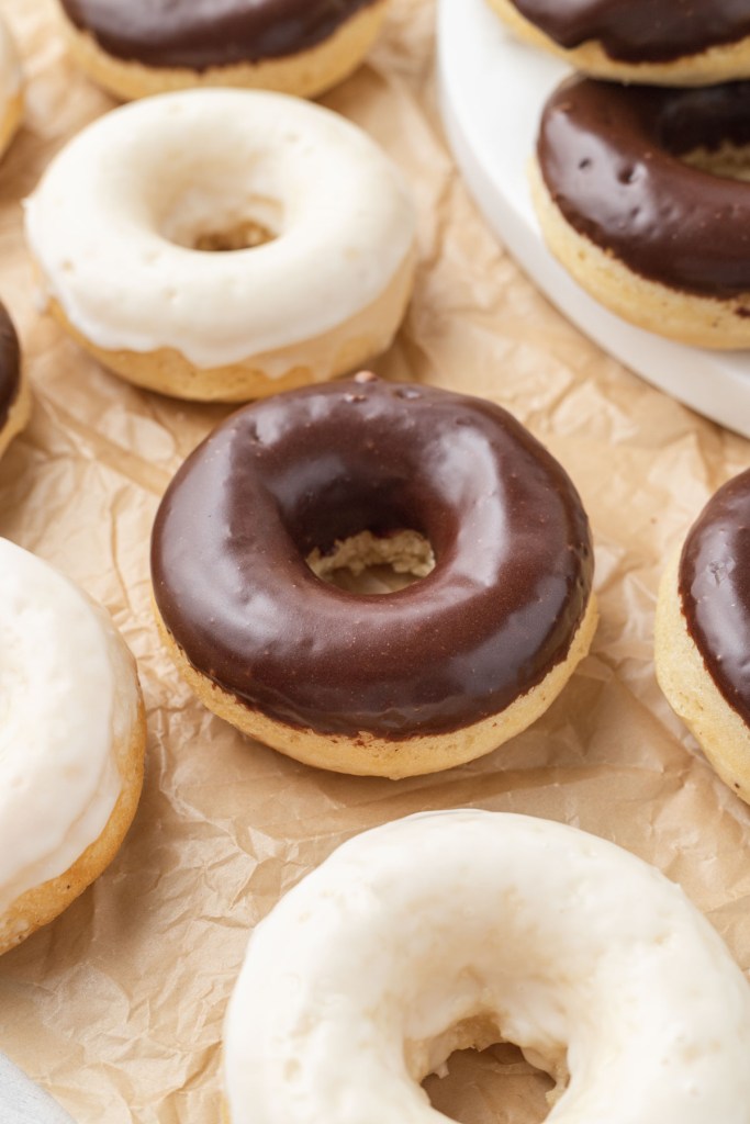 Baked cake donuts with icing on parchment paper. 