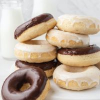 Several baked donuts stacked on top of each other. The donuts are coated in chocolate and vanilla icing.