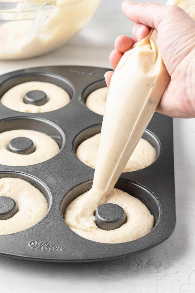 Donut batter being piped into a donut pan.