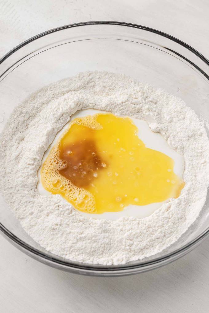 An overhead view of the dry and wet ingredients for baked donuts in a mixing bowl.