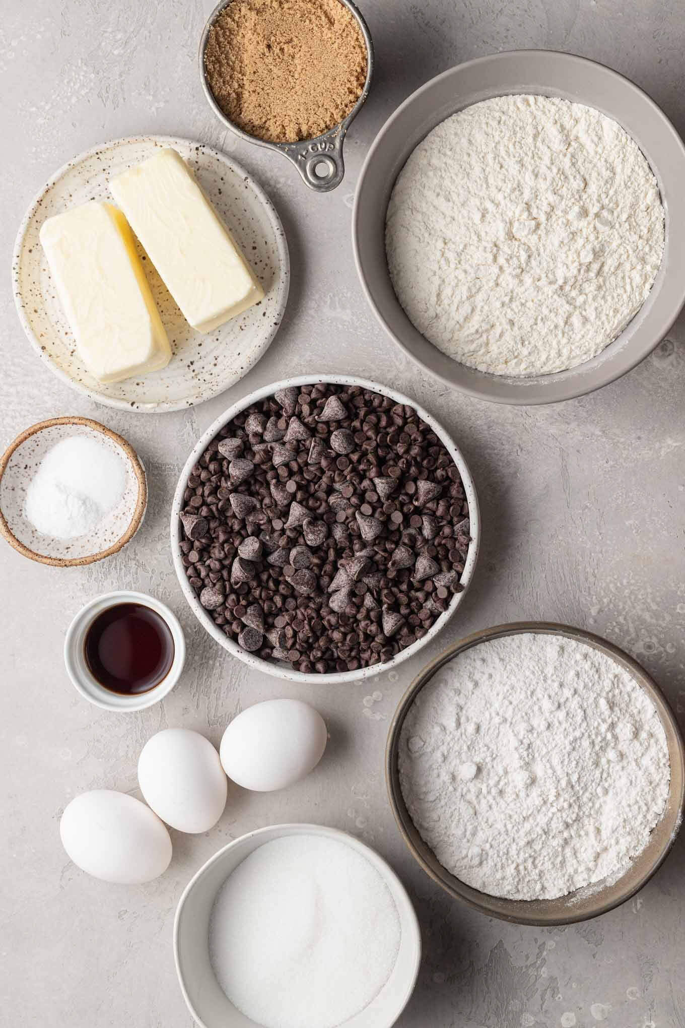 An overhead view of the ingredients needed to make these chocolate chip cookies in various bowls and measuring cups.