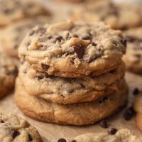 Three thick bakery style chocolate chip cookies stacked on top of each other.