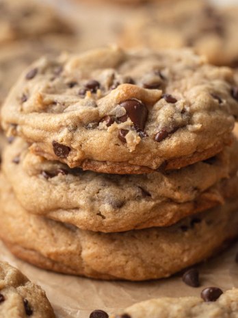 Three thick bakery style chocolate chip cookies stacked on top of each other.