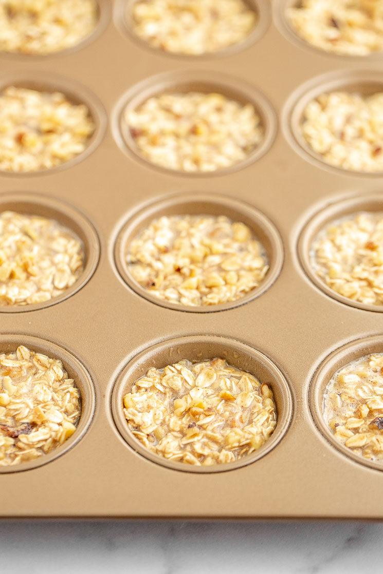 A copper colored muffin pan with the banana oatmeal mixture ready to be put into the oven for baking.