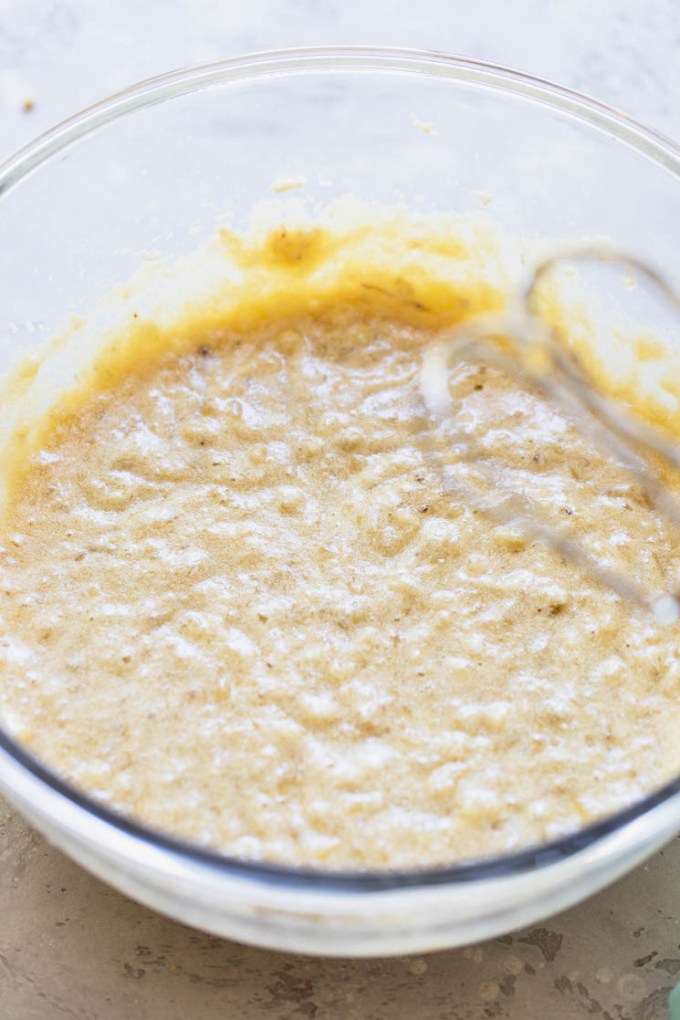 A glass bowl with the wet ingredients for banana bread mixed together.