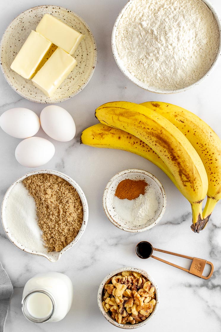 All of the ingredients needed to make a banana cake on a marble surface.