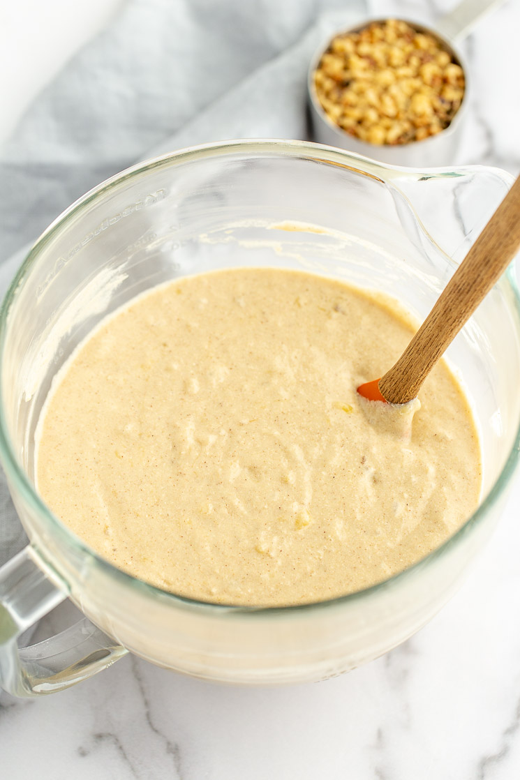 A glass mixing bowl filled with banana cake batter.