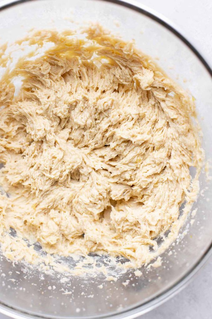 An overhead view of a glass mixing bowl of the wet ingredients for banana cookies.