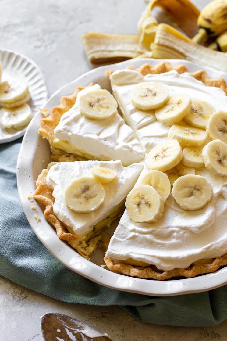 A finished banana cream pie with one piece removed and two more separated to show the layers and texture of the pie.