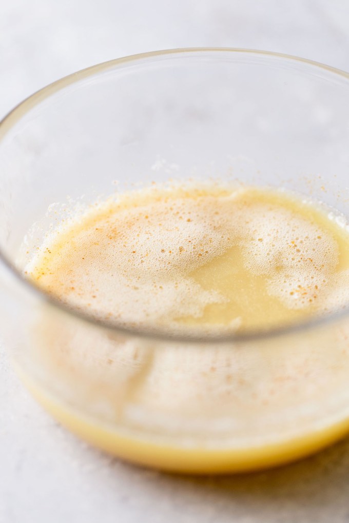 A glass mixing bowl holding cooled browned butter.