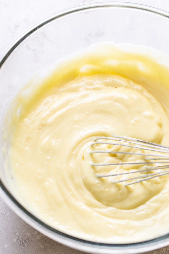 Chilled vanilla pudding in a glass bowl with a whisk.