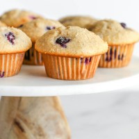 Blueberry muffins on top of a marble cake stand.