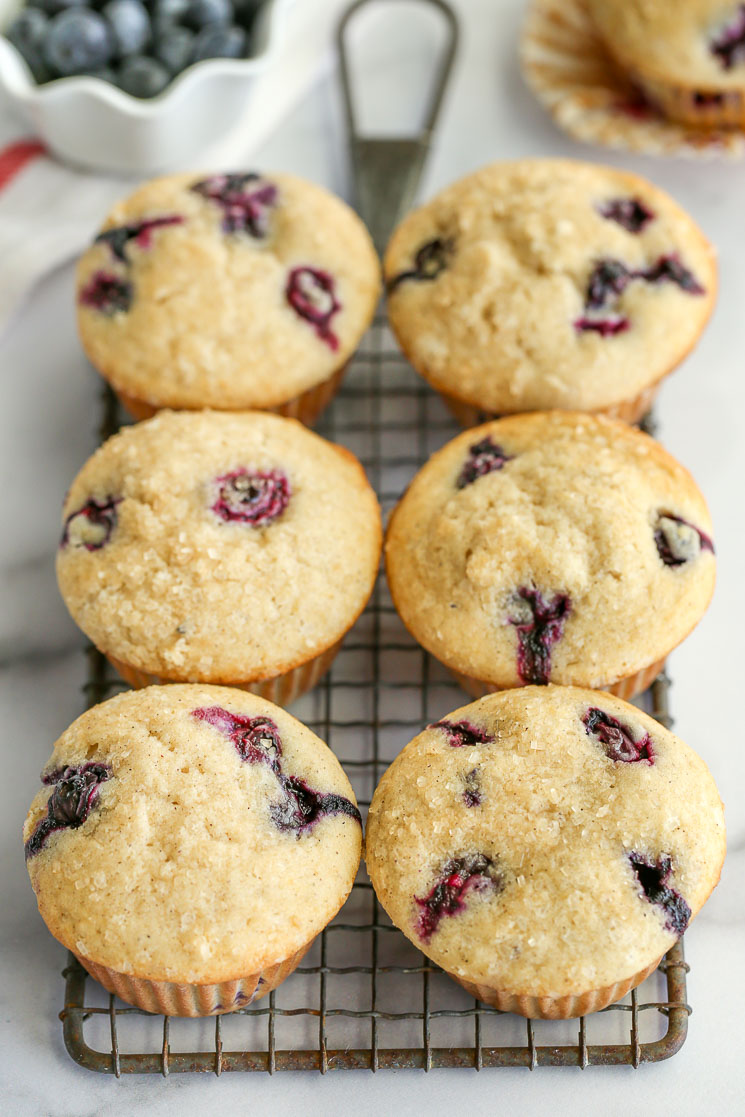 Blueberry muffins on top of a safety grater with blueberries in the background. 