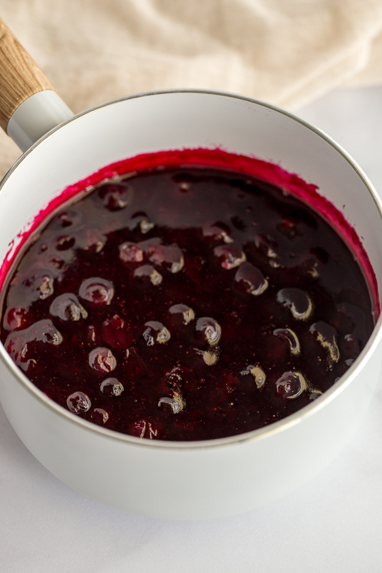 A white saucepan filled with the cooked blueberry sauce.