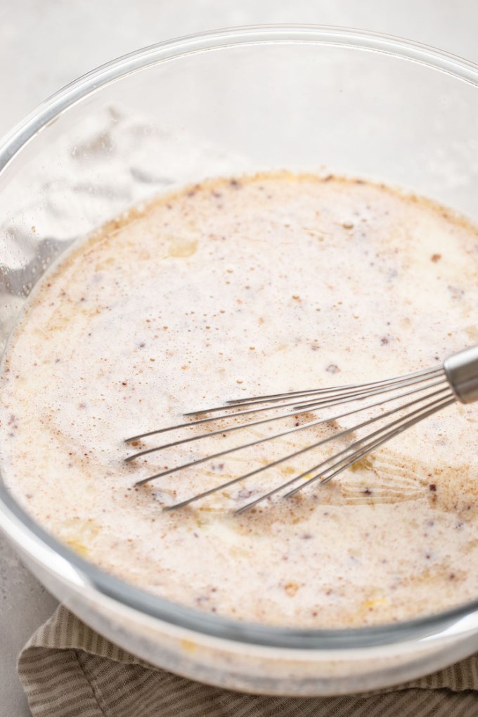 The custard mixture being whisked together in a glass bowl.