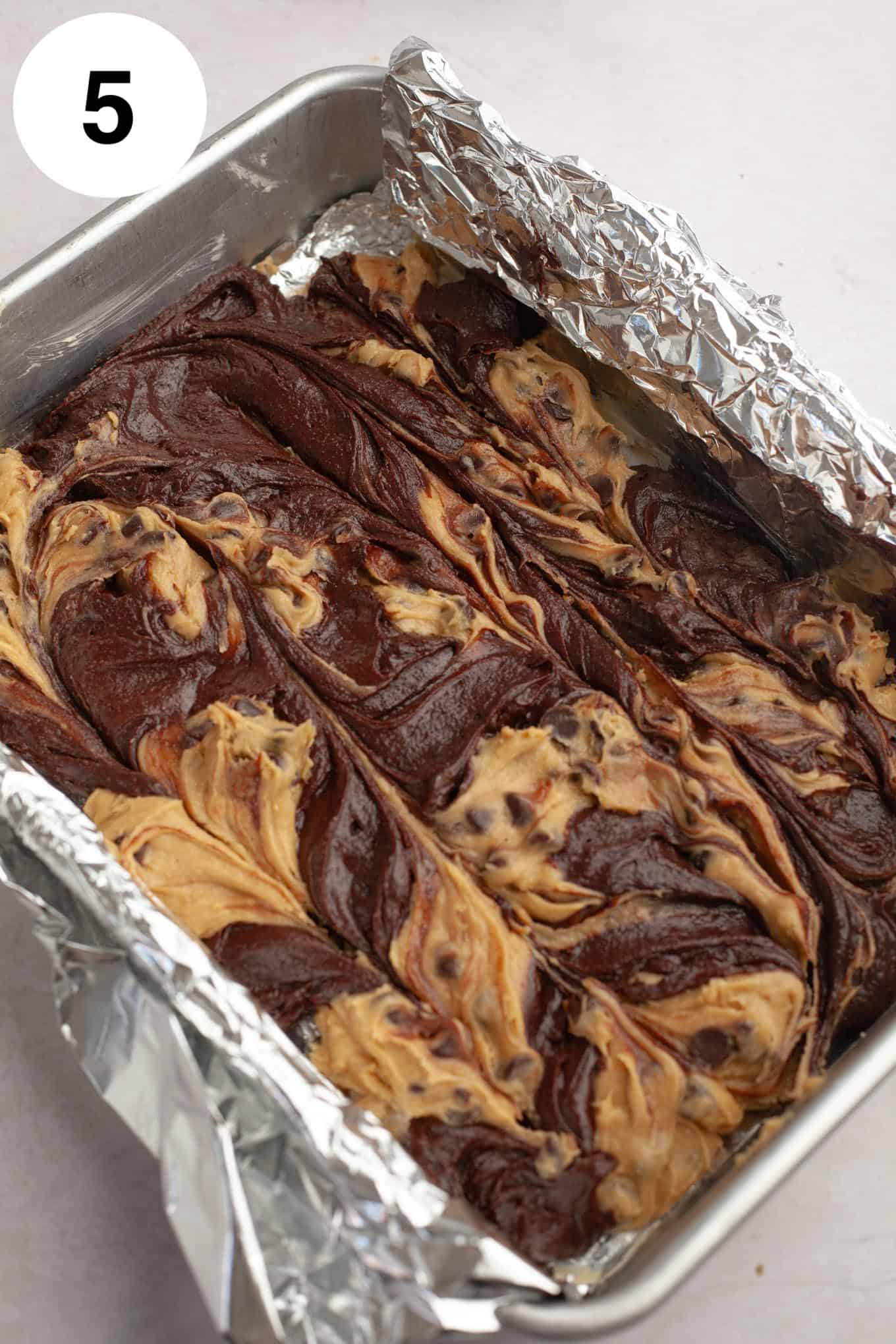 An overhead view of raw brookie batter in a foil-lined pan. 