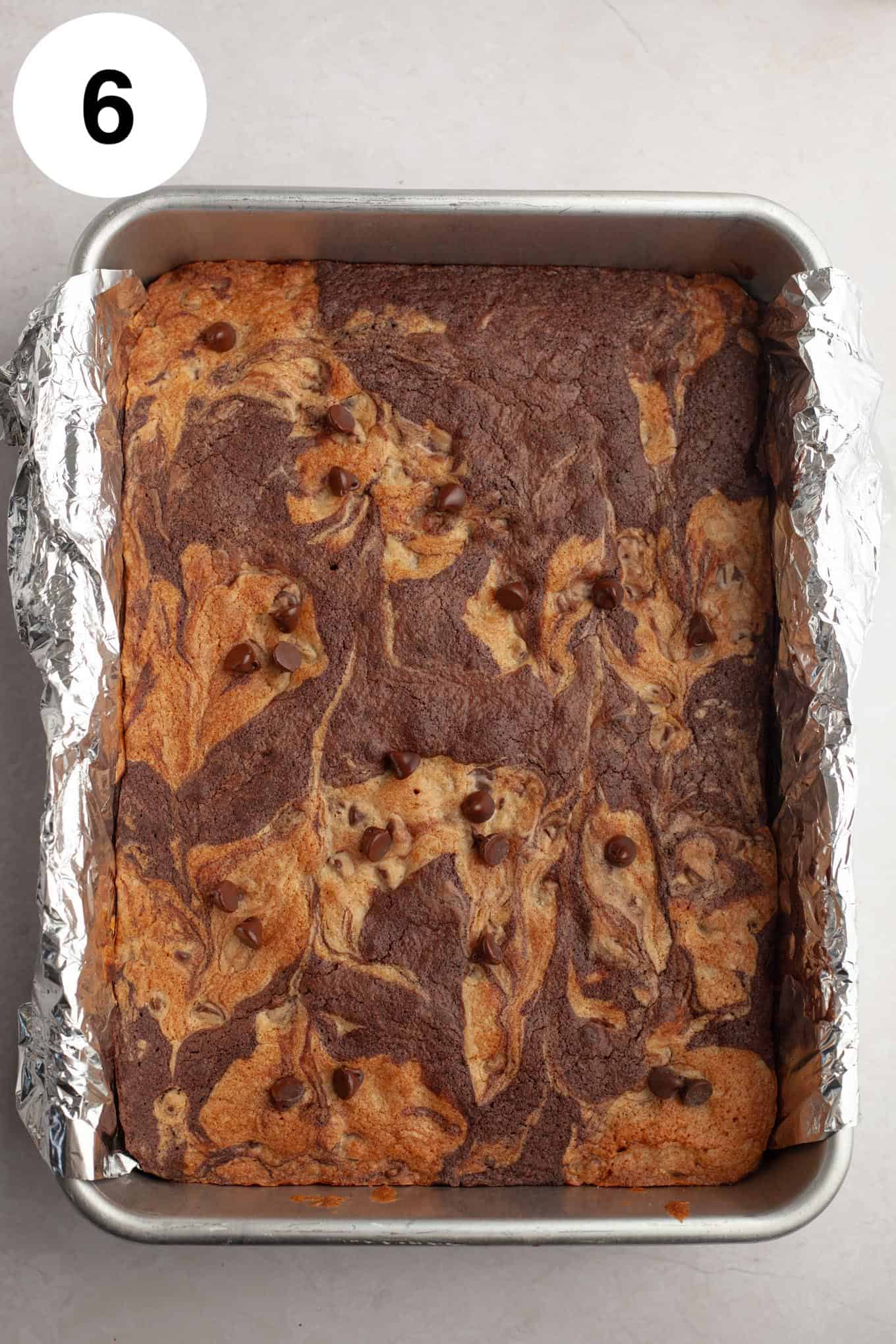 An overhead view of baked brookie bars in a foil-lined pan. 