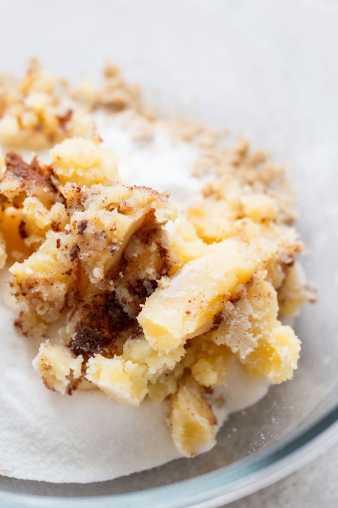 A glass mixing bowl holding the brown butter and sugars for the cookies.