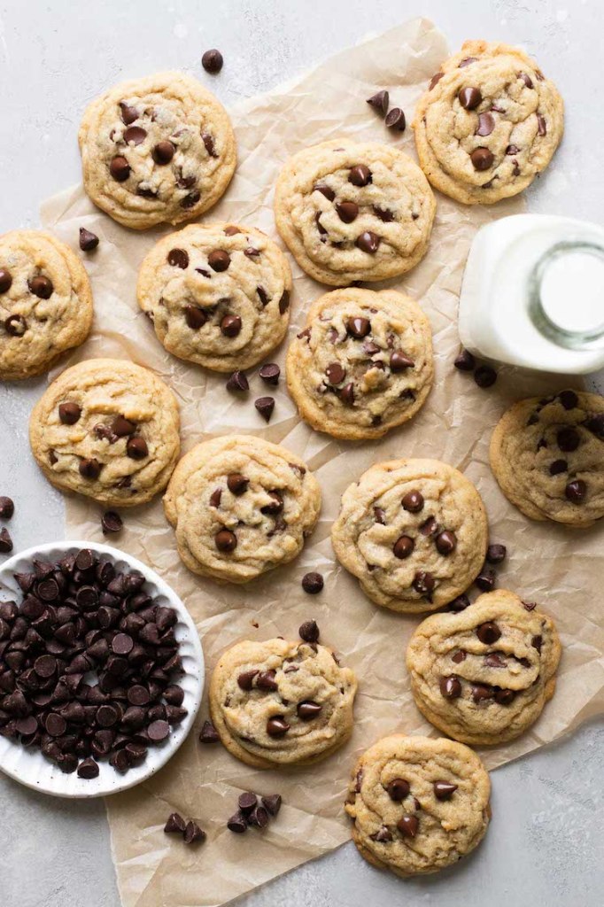 A bakers dozen of brown butter chocolate chip cookies laid out on a brown piece of parchment paper.