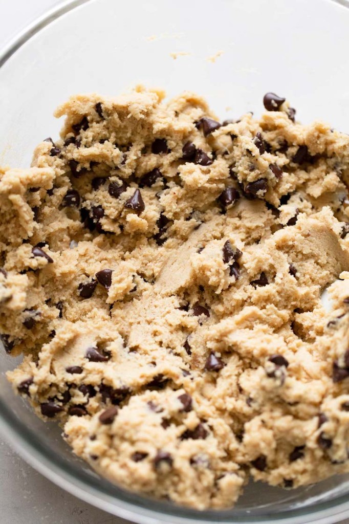 A glass mixing bowl holding the finished brown butter chocolate chip cookie dough. 