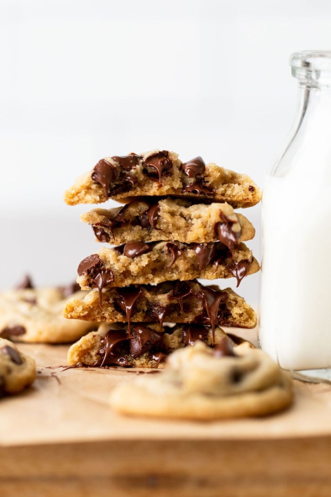 A stack of cookies that have been broken in half showing the texture and melty chocolate chips.