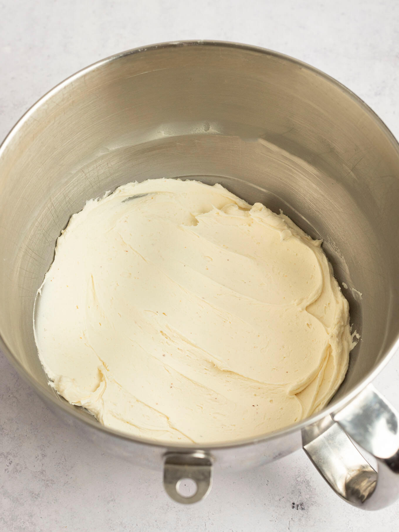 Brown butter frosting mixed together in the bowl of a stand mixer.