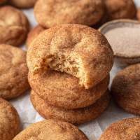 Three snickerdoodles stacked on top of each other. The top cookie has a bite missing.