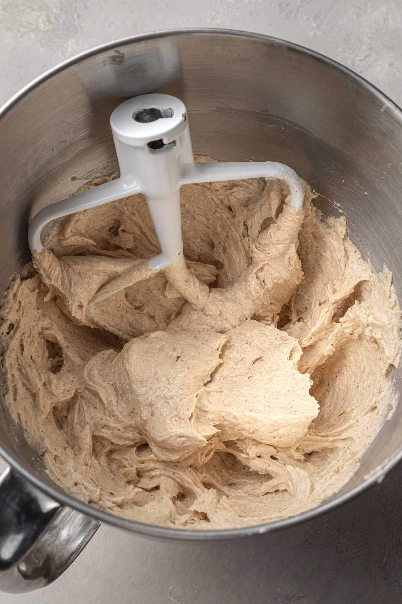 An overhead view of the wet ingredients needed for snickerdoodle cookies in a mixing bowl, with a paddle attachment. 