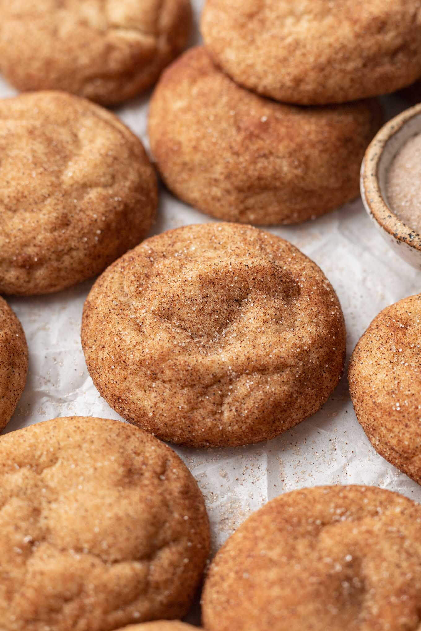 A close up view of snickerdoodles made with brown butter, on parchment paper. 