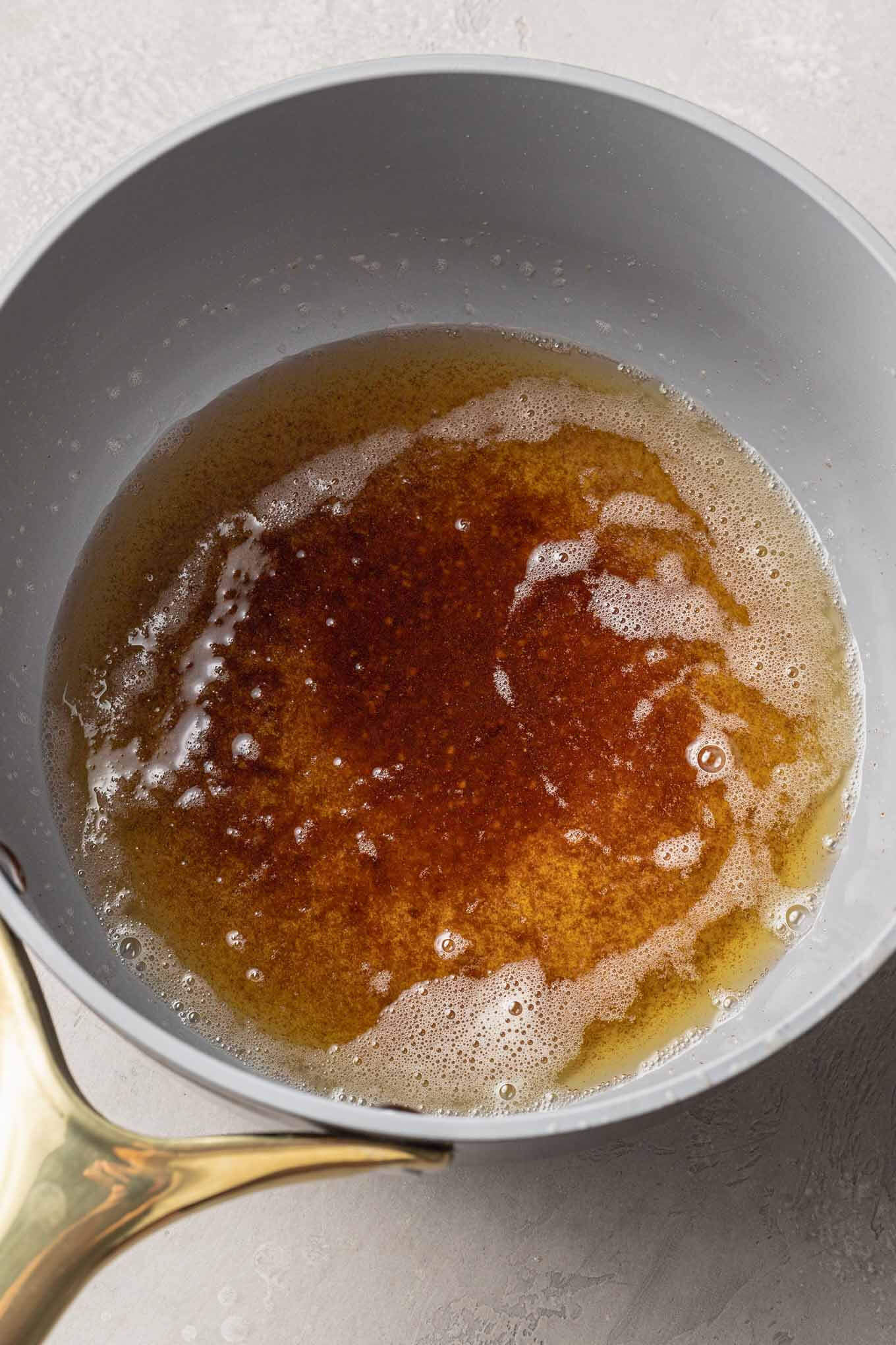 An overhead view of browned butter in a saucepan. 