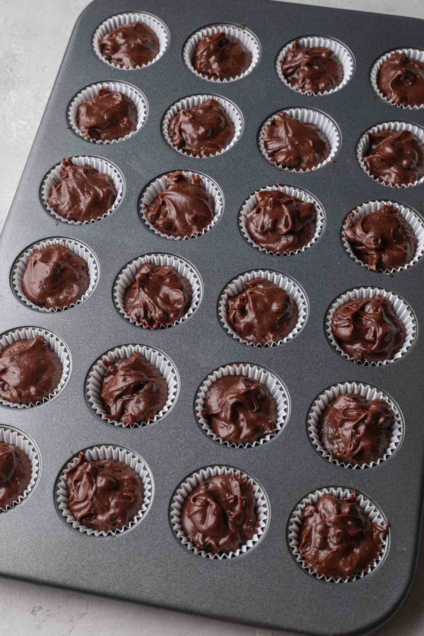 An overhead view of mini brownies in a mini muffin pan, ready to be baked. 