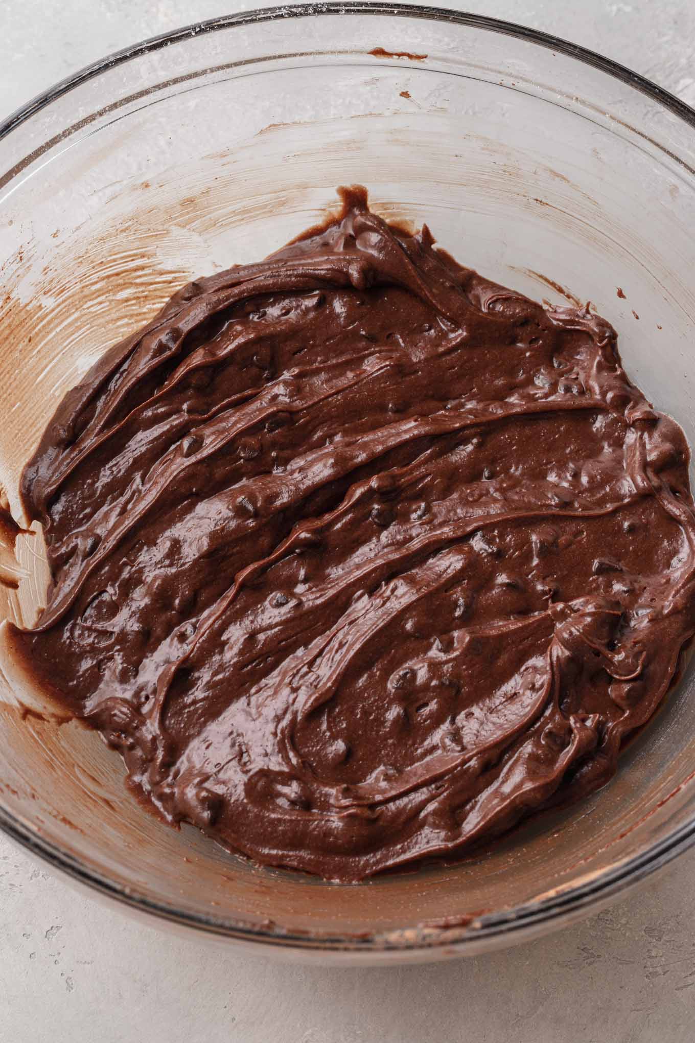 An overhead view of brownie batter in a glass mixing bowl. 