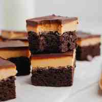 A stack of two buckeye brownies, the top brownie has a bite missing.