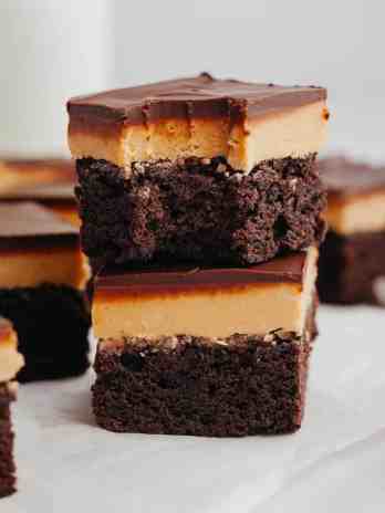 A stack of two buckeye brownies, the top brownie has a bite missing.