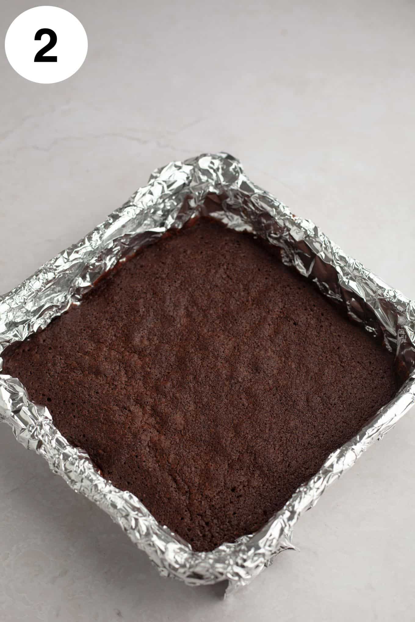 An overhead view of baked brownies in a foil-lined pan. 